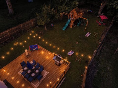 After dark, the whole backyard glows. String lights over the deck, the playground lit up, cornhole ready in the grass. The kind of evening that keeps going long after dinner.