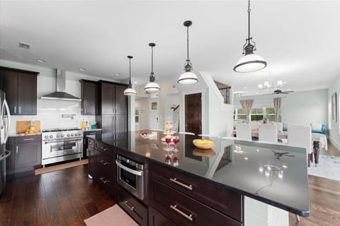 Kitchen with a large granite island, stainless steel appliances, and custom dark wood cabinetry. The open layout seamlessly connects to the dining and living spaces, making it ideal for entertaining