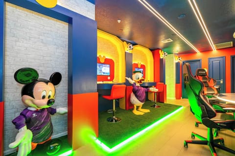 Dive into fun in this vibrant game room with playful Mickey and Donald décor, neon accents, and cozy gaming chairs-perfect for all ages to enjoy a whimsical retreat!