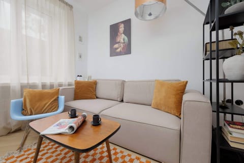 A cozy living room with a beige sectional sofa, orange accent pillows, and a black coffee table on a patterned rug.