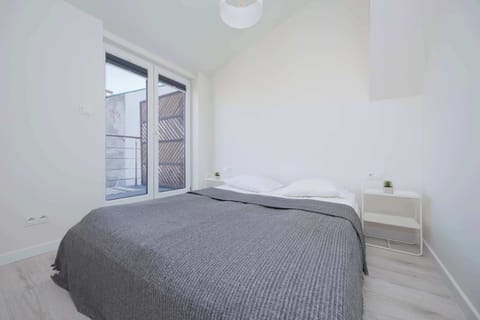 A cozy bedroom with a gray bedspread and sloped ceiling, bathed in natural light.