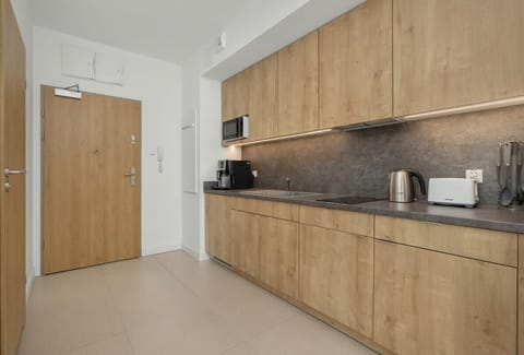 A compact, clean kitchen space with wooden cabinets and stainless steel appliances. It provides all essentials in a neat layout.