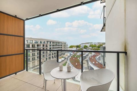 A balcony view with modern chairs overlooking a vibrant residential complex. The perfect spot to unwind outdoors and enjoy the view.