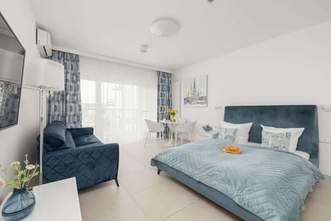 A cozy living room space with a stylish sofa bed and a TV area for relaxing evenings. Light-toned walls and modern decor create a fresh and inviting atmosphere.