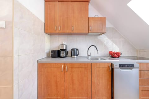A traditional-style kitchen with wooden cabinets, white countertops, and modern appliances, including a kettle and coffee maker.