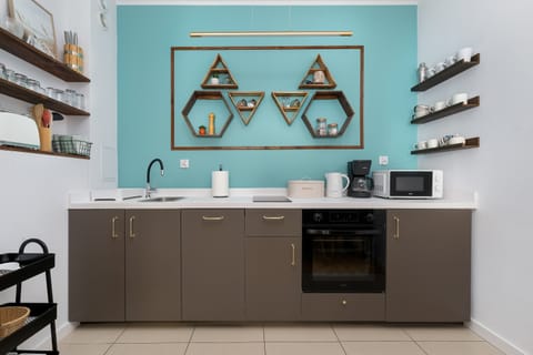 Modern kitchen with open shelves, turquoise wall, and built-in appliances.