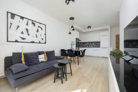A bright and spacious living room with a comfortable gray sectional sofa, modern artwork, and a large window letting in natural light.