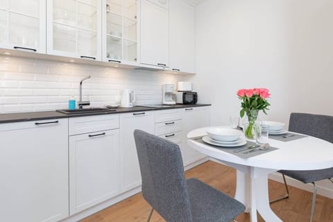 A compact kitchen with white cabinets, a microwave, and a small dining area adjacent to it.