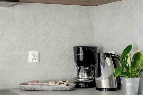 A coffee maker and kettle on a concrete countertop offer a practical setup for aromatic mornings.
