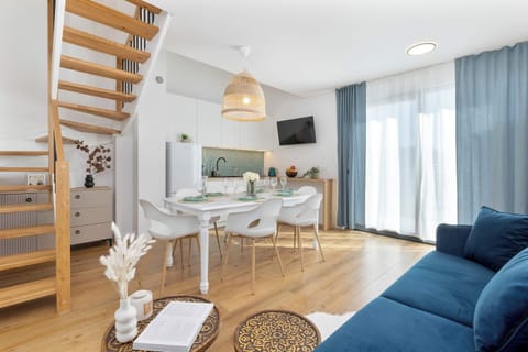 In the central part of the room is a white dining table with four chairs, inviting people to eat together.