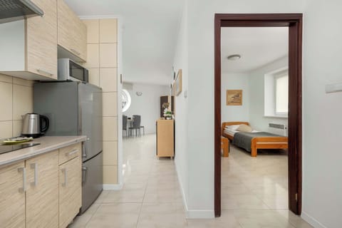 A view into a hallway with beige cabinets, opening to a bedroom with twin wooden beds and orange linens.