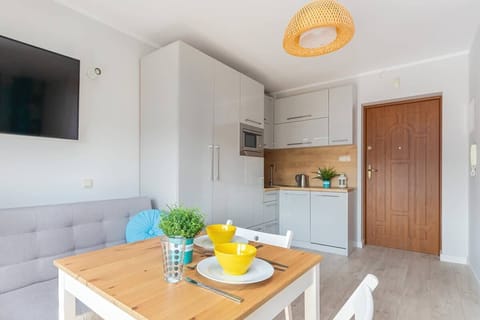 Kitchen cabinets, a wooden table with chairs, and a modern light fixture.