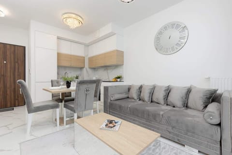 A modern open-plan living room with a gray sofa, dining table, and stylish kitchen.