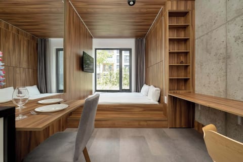 Cozy studio with a comfortable double bed, TV and desk with chair.
