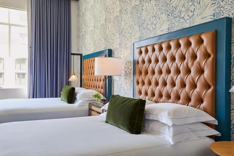 Unwind in crisp linens beneath plush tufted headboards, serene comfort.