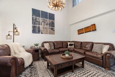Cozy sectional, antler chandelier, ski-lift artwork, and vintage sled wall decor