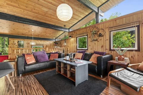 The living are has two sofas, a coffee table, wood interior and large windows