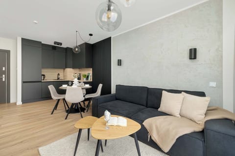 A stylish living room with a dark sectional sofa, round nesting tables, and a mounted TV, complemented by minimalist decor.