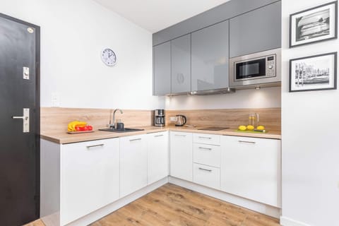 Funkcjonalny aneks kuchenny z mirofalówką i płytą grzewczą zapewnia miejsce do gotowania.