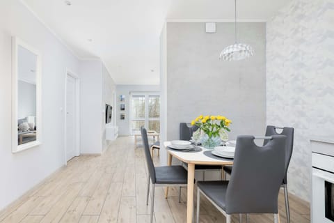 A bright and open dining space with a modern white kitchen featuring elegant finishes and ample storage.