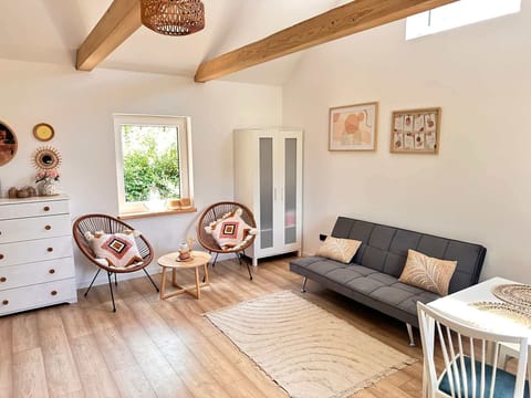  A cozy living room space with a comfortable sofa and natural light streaming through large windows. Perfect for relaxing or spending time with loved ones.