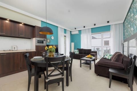 A modern open-plan living room with a sofa, dining table, and kitchen area. Ideal for spending quality time with friends or family.