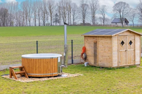 A wooden hot tub placed in the backyard, offering a tranquil space for relaxation in a natural setting.