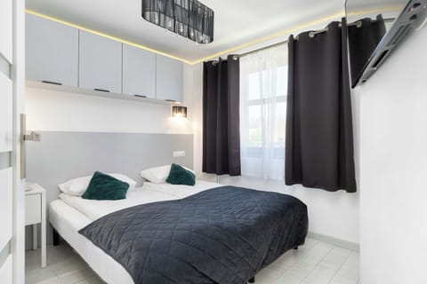 A modern bedroom with large double bed, bedside tables, and stylish curtains.