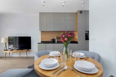 Open-plan living space with a dining table, gray sofa, and large windows.