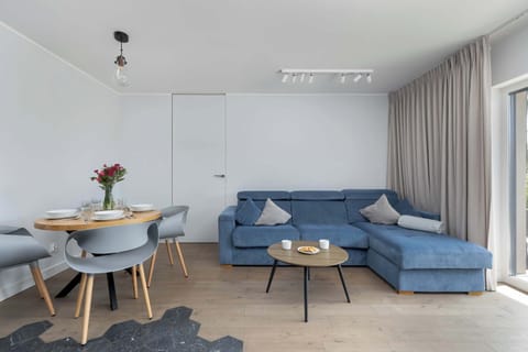 Living and dining area with a round table, modern gray sofa, and floor-to-ceiling curtains.