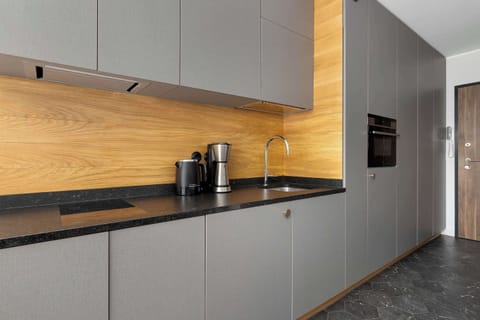 Modern kitchen with wooden backsplash and integrated appliances.