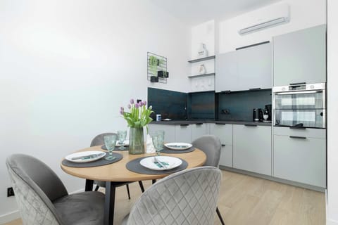 Spacious kitchenette with open plan dining table, equipped with modern furniture and appliances such as oven, refrigerator, coffee maker, ideal for cooking and eating together.