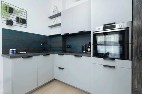 Elegant kitchen with white cabinets, contrasting black countertops and modern appliances for cooking comfort.