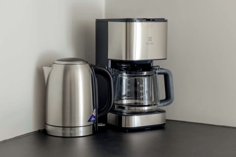 A coffee station with a coffee maker, a kettle, and a dark countertop. The setup is perfect for a morning brew.