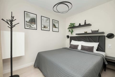 A modern bedroom with a double bed, wall-mounted reading lamps, and minimalist décor. The space is bright and inviting, ideal for restful sleep.