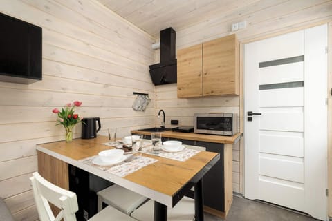 Dining and kitchen area featuring wooden cabinets, small appliances, and a compact dining table with stools.