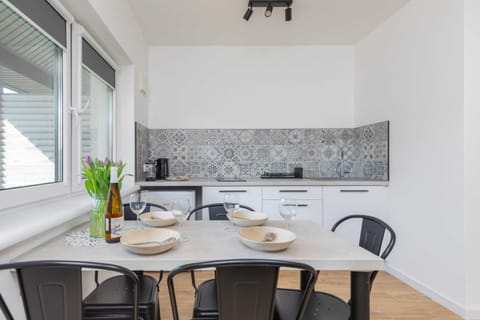 A bright, airy dining area with a sleek black dining table and chairs. Large windows offer an inviting view of the outdoors.