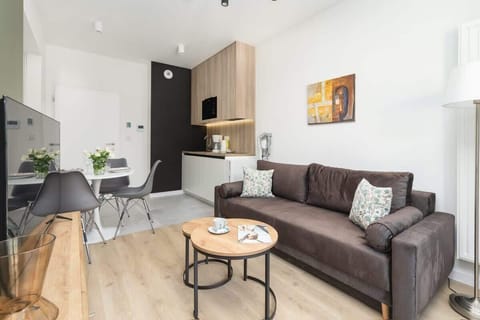 A wide view of the open-plan living and dining area, featuring a gray sofa, dining table, and minimalist decor.

