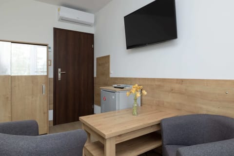 Welcoming living area with a wooden coffee table, a flat-screen television, and two armchairs.