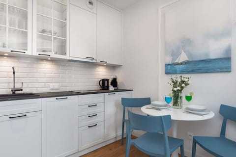 A fully equipped kitchen with white cabinetry, a tiled backsplash, and modern appliances.