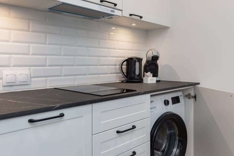 A fully equipped kitchen with white cabinetry, a tiled backsplash, and modern appliances.