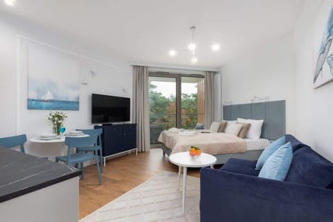 A bright living space with a small dining table, a comfortable sofa, and access to a balcony.