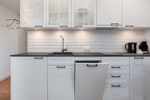 A fully equipped kitchen with white cabinetry, a tiled backsplash, and modern appliances.