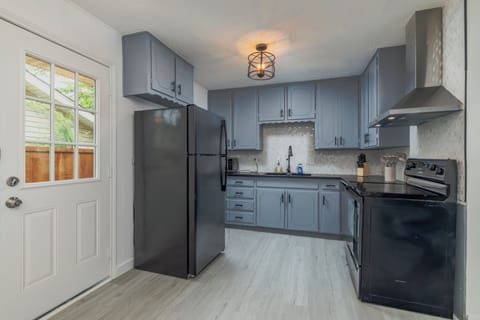 Fully stocked kitchen with a stainless steel range hood and cooking essentials.