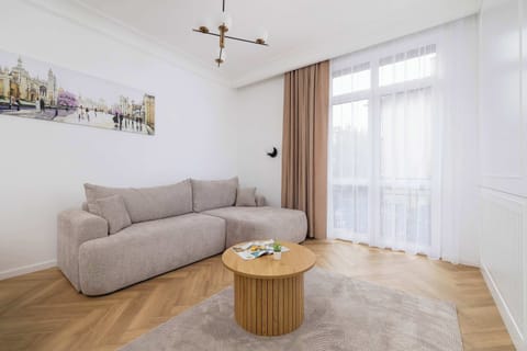 Beige and cosy living room with double sofa bed, coffee table, television, and dining table with chairs.