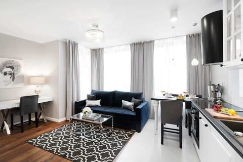 Spacious and elegant living room with dining area, functional kitchenette, desk with chair for comfortable remote work, and dark blue sofa.