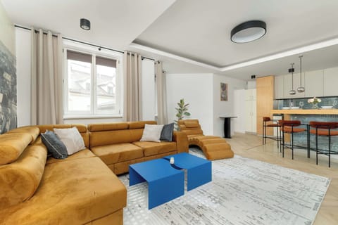 The living room showcasing a mustard sofa with vibrant pillows. A sleek coffee table and stylish décor elements complement the modern aesthetic.