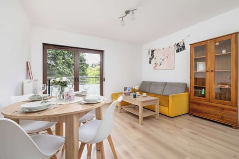 Bright living room with a sofa bed, TV and dining area.
