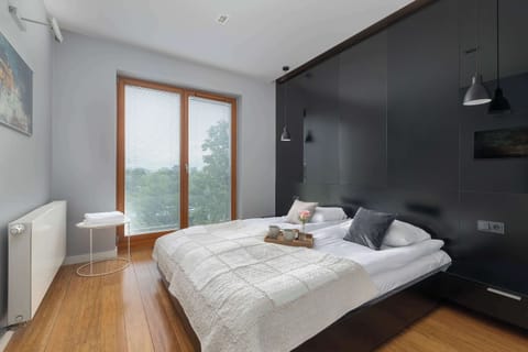 Cozy bedroom with dark accent wall, wooden floor, and plenty of natural light.