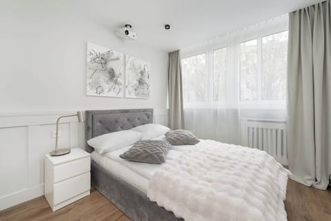 A stylish bedroom with a comfortable bed, soft bedding, and subtle wall decorations. Neutral tones dominate the decor.